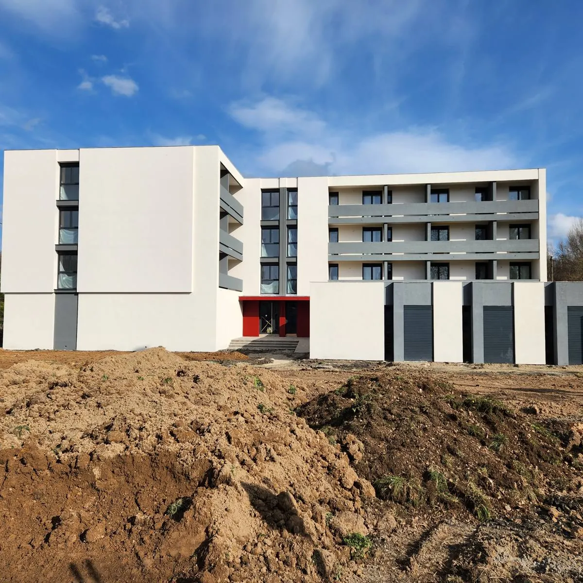 Même immeuble après travaux : façades blanches et grises, entrée rouge