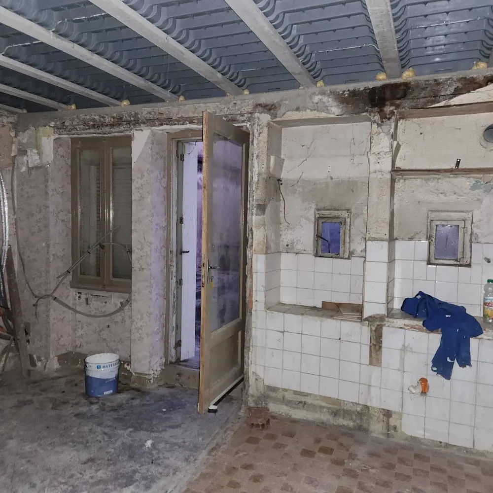Pièce avant travaux : murs dégradés, ancien carrelage et plafond dégagé